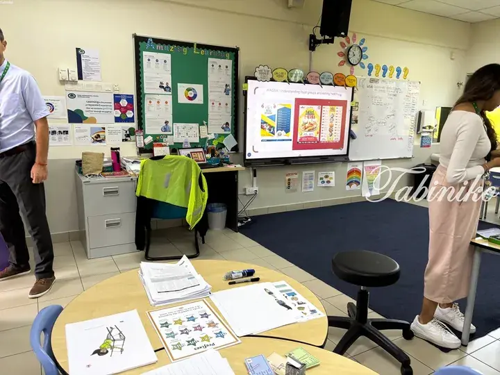 Teachers observe a classroom lesson on healthy eating displayed on a digital screen.