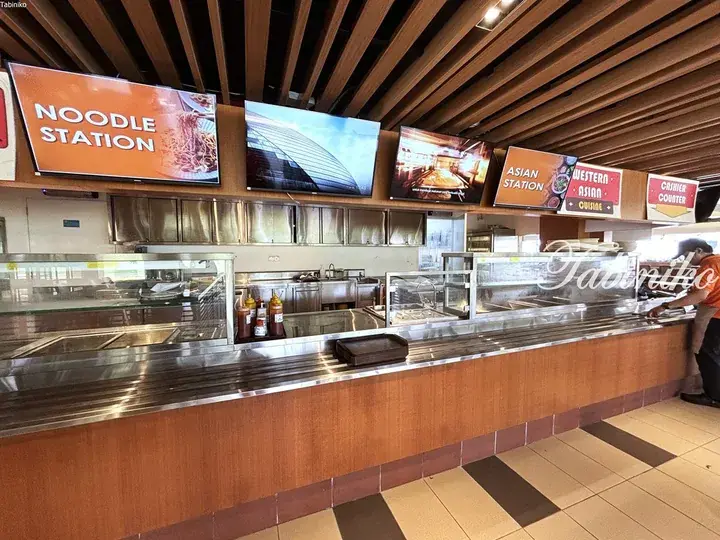 Food court serving noodle, Asian, and Western cuisine with digital menu screens and a cashier counter.