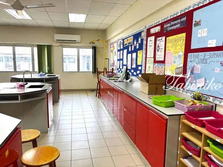 Bright science classroom with red cabinets, lab benches, and educational posters on chemistry topics.