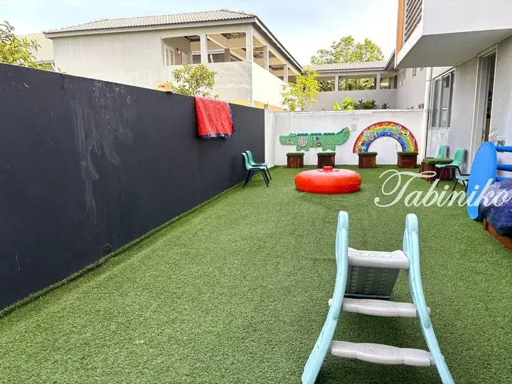 Outdoor play area with artificial grass, colorful wall art, and child-friendly furniture at a Malaysia property.