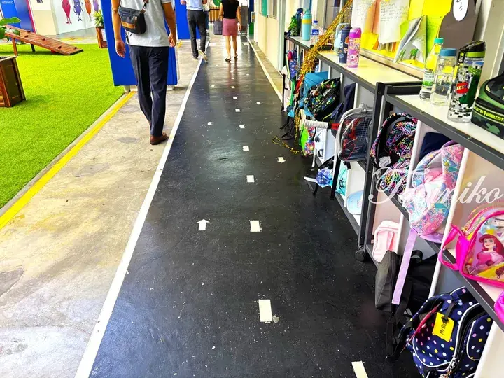 School hallway with black floor arrows, lockers, and students walking in a Malaysian educational facility.