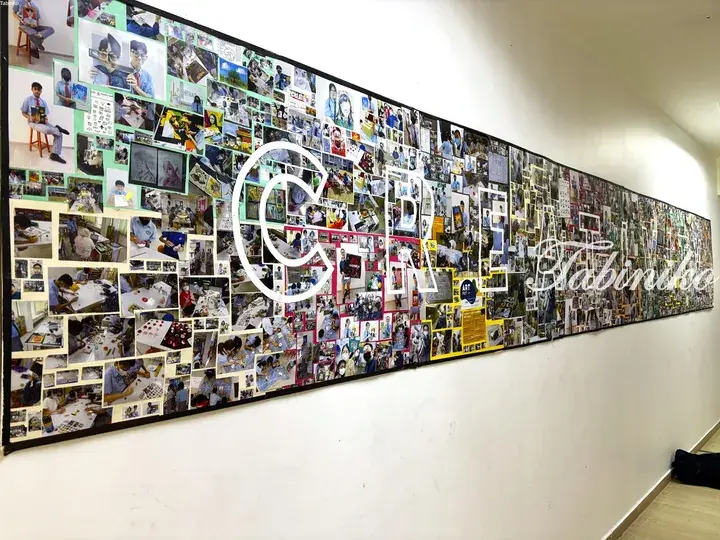 A long hallway wall covered in a vibrant collage of photos showcasing student activities and art at Tabiniko.