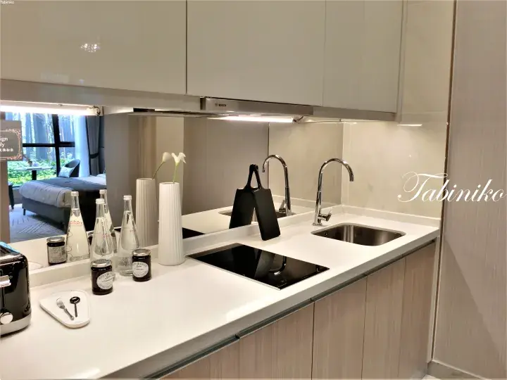 Modern kitchenette with white countertops, Bosch appliances, and a sink in a serviced residence.
