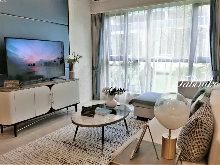 Modern living room interior with a large TV, white cabinet, and floor-to-ceiling windows overlooking a green garden.