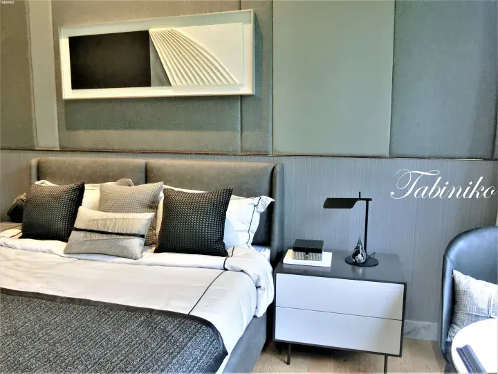 Modern luxury bedroom with grey upholstered bed, textured pillows, and sleek nightstand in a high-end property.