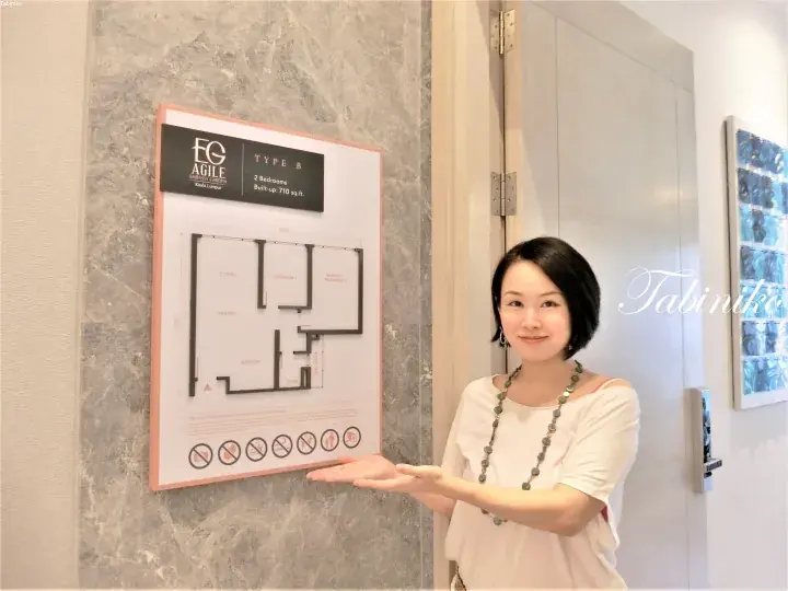 Woman presenting a floor plan for a 2-bedroom Type B unit at EG Agile Embassy Garden in Kuala Lumpur.