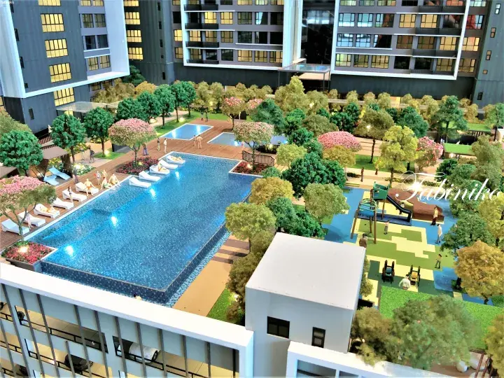 Architectural model of a modern condominium featuring a large swimming pool, landscaped gardens, and children’s playground.