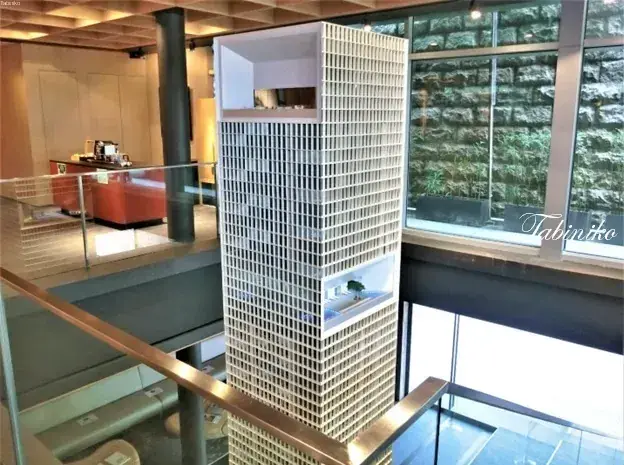 Detailed architectural model of a modern high-rise building displayed in a bright, contemporary showroom.