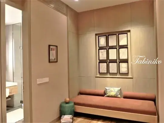 Cozy wooden daybed with cushions in a modern interior featuring a framed wall art and bathroom entrance.