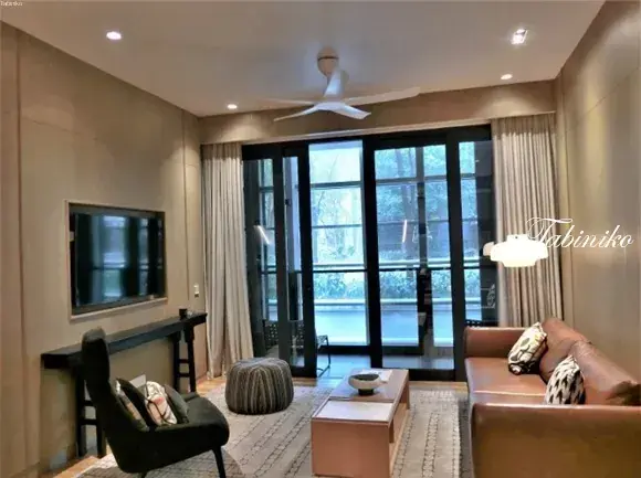 Modern living room with brown leather sofa, TV, and glass doors leading to a balcony.