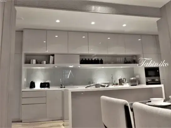 Modern white kitchen with sleek cabinetry, open shelving, and a breakfast bar in a contemporary home.