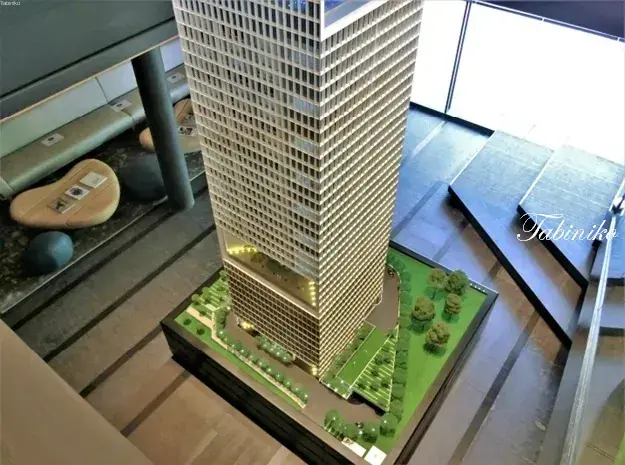 Architectural model of a modern high-rise building with landscaped greenery and surrounding pathways.