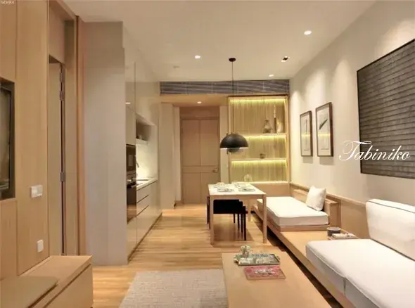 Modern minimalist dining area with wooden table, bench seating, and built-in kitchen in a compact apartment.