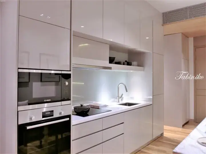 Modern white kitchen with built-in Bosch oven, induction cooktop, and sleek cabinetry in a contemporary home.