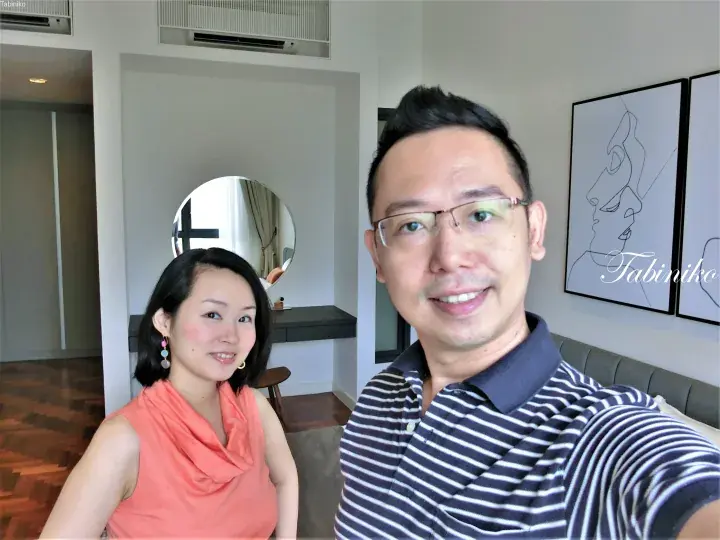 Couple smiling in a modern apartment bedroom with wooden floors and minimalist wall art.