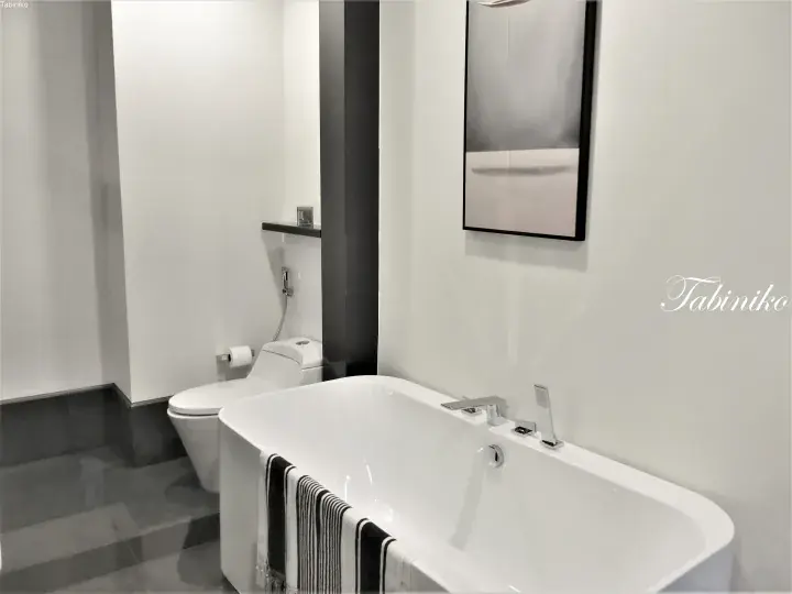 Modern bathroom with a freestanding white bathtub, black and white striped towel, and minimalist decor.