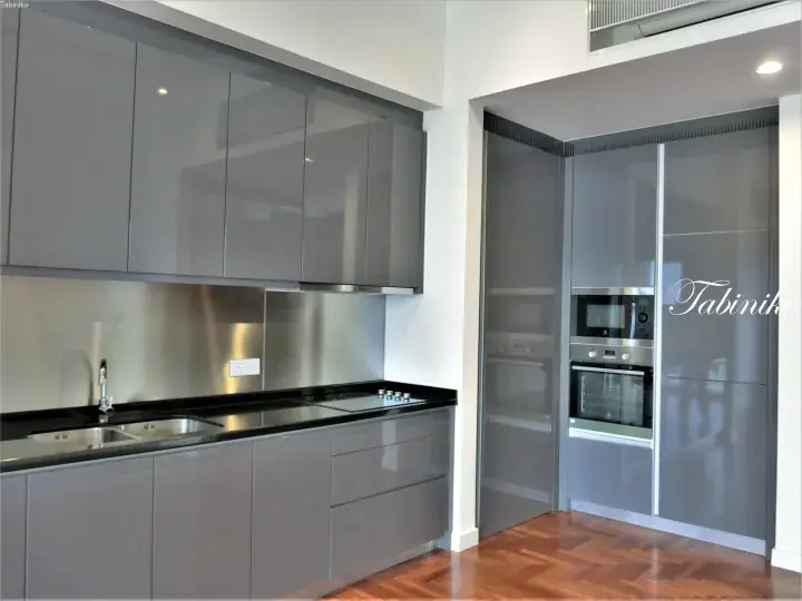Modern kitchen with grey glossy cabinets, black countertops, and stainless steel appliances in a Malaysia property.