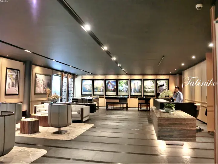 Modern luxury real estate showroom with property displays, seating area, and reception desk.