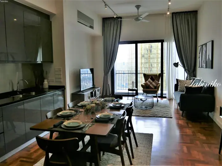 Modern apartment interior with dining table, kitchen, and balcony view of city buildings.