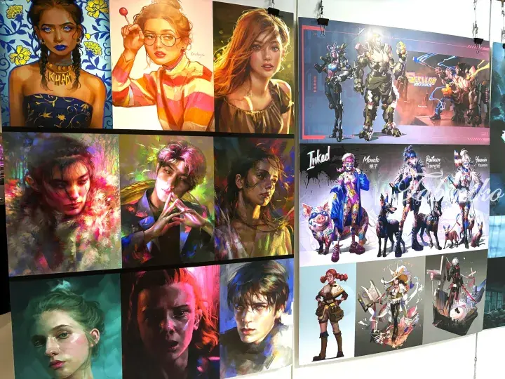 Wall display of vibrant digital art prints featuring fantasy characters, sci-fi concepts, and diverse portraits in an exhibition setting.