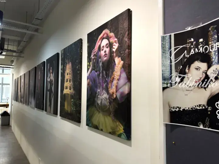 A gallery wall displaying large fashion photography prints featuring models in elaborate outfits and vibrant colors.