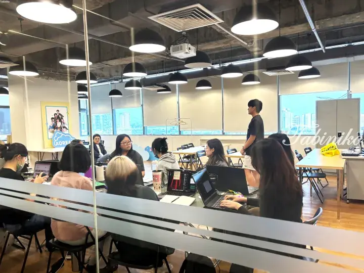 Group of people working on laptops in a modern co-working space with city views.