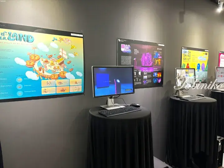 Digital media design exhibition displays featuring interactive posters and computer workstations at a showcase event.