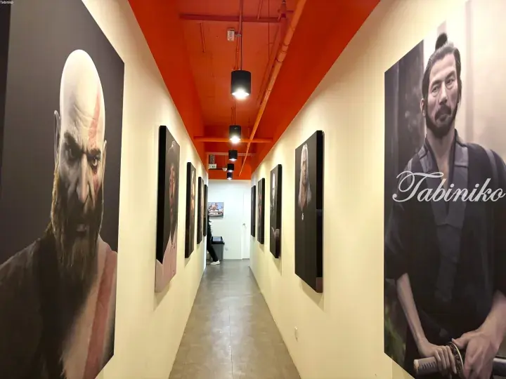 Corridor with large video game character portraits on cream walls and an orange ceiling.
