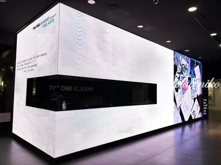 The One Academy School of Fine Arts graduation exhibition entrance with LED display showing event details and artwork.