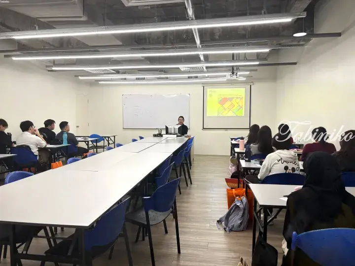 Instructor teaching design fundamentals to students in a modern classroom with projector screen and whiteboard.