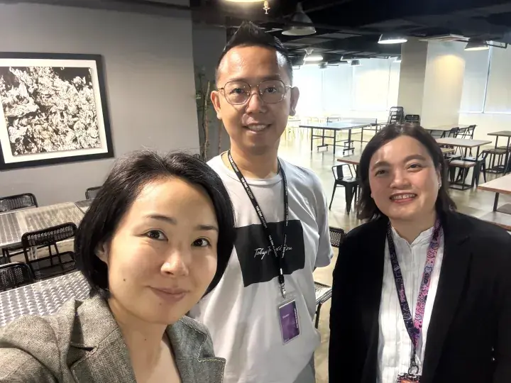 Three smiling people wearing lanyards at The ONE Academy, a creative campus in Kuala Lumpur, Malaysia.