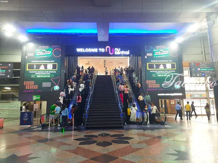 Crowds of people using escalators and stairs at the entrance of NU Sentral shopping mall in Kuala Lumpur.