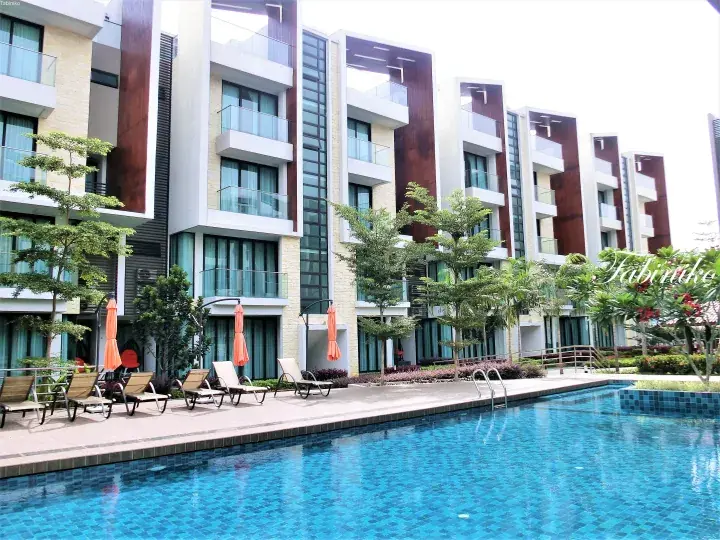 Modern resort building with poolside lounge chairs and orange umbrellas overlooking a swimming pool