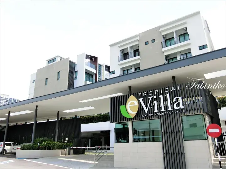 Modern white building entrance of Tropical eVilla Luxury Homestay Villa with a large canopy and reception area.