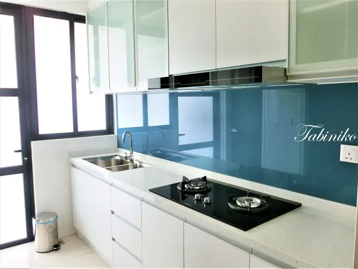 Modern kitchen with white cabinets, blue glass backsplash, and stainless steel sink in a Malaysian property.