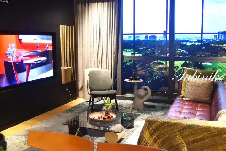 Modern luxury living room with pink sofa, large TV, and floor-to-ceiling windows overlooking a golf course and city skyline.