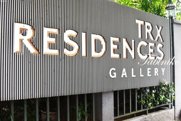 Close-up of the TRX Residences Gallery sign featuring white lettering on a dark corrugated metal wall.