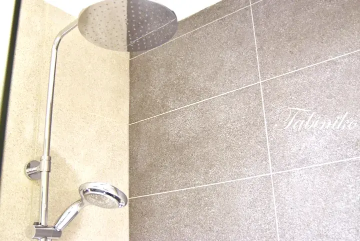 Modern bathroom shower with chrome fixtures and beige and grey tiled walls.