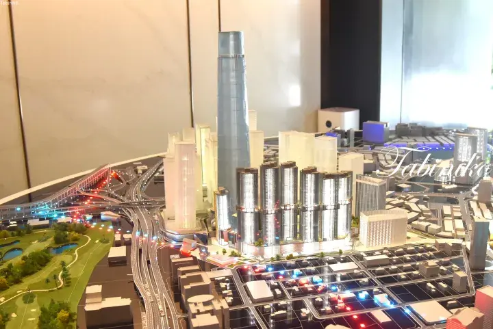 Architectural model of a modern Malaysian city featuring a tall skyscraper, illuminated highways, and surrounding high-rise buildings.