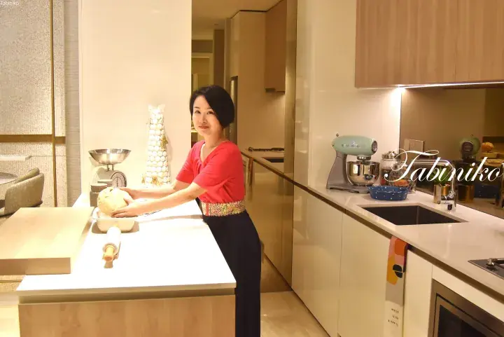 A woman kneading dough in a modern kitchen with a SMEA mixer and wooden accents.