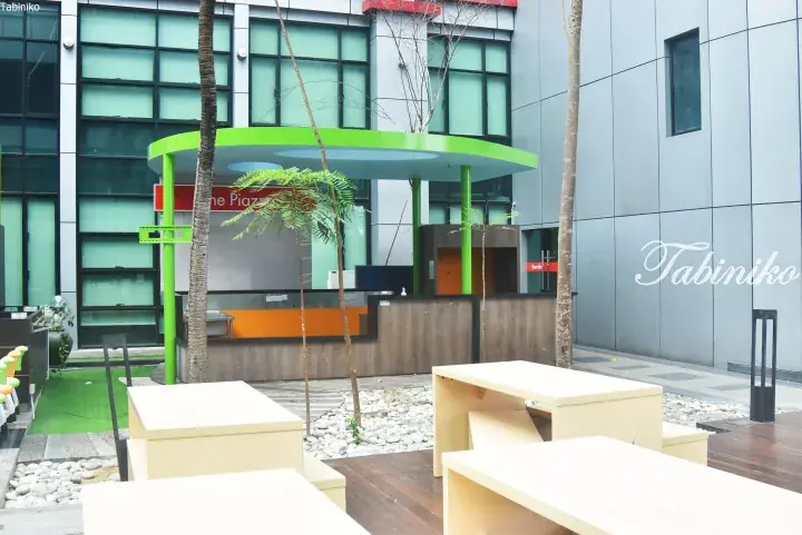 Modern outdoor co-working space with wooden desks and green accents at a property in Malaysia.