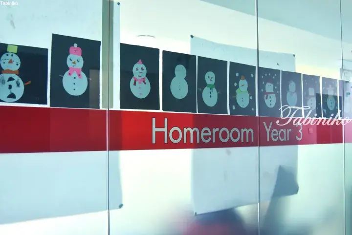 Frosted glass door with red stripe reading Homeroom Year 3, displaying children’s snowman artwork.
