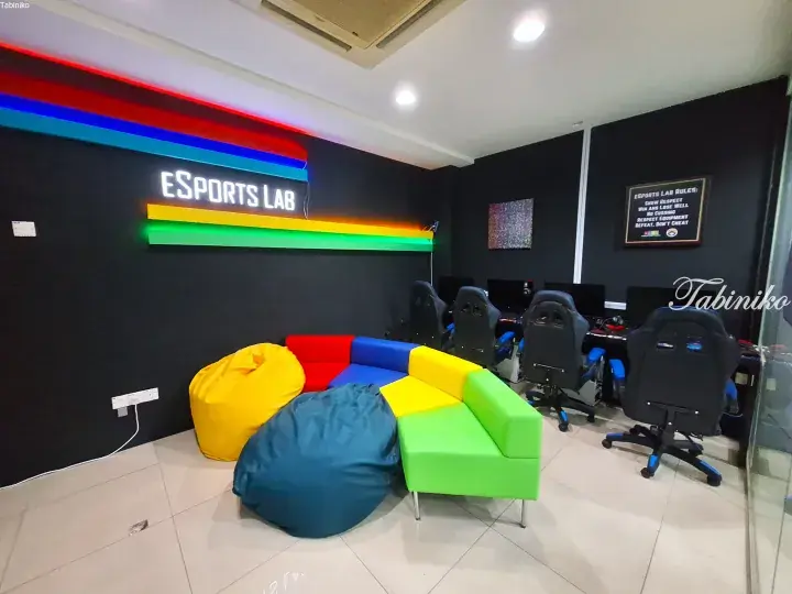 Colorful bean bags and gaming chairs in the Esports Lab lounge area with neon signage.