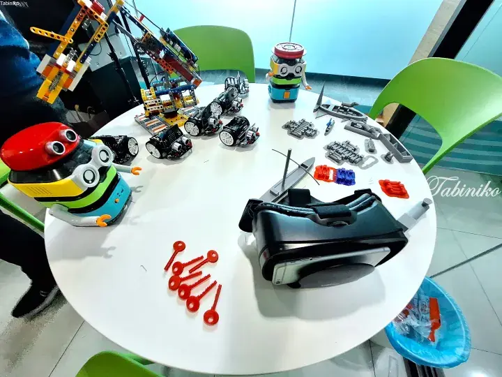 Educational robotics kits, a VR headset, and building blocks arranged on a white table for STEM learning activities.