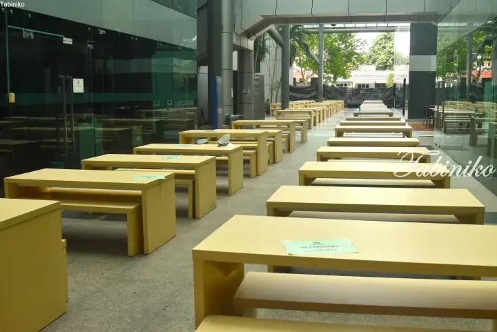 Rows of yellow tables and benches in a modern school canteen with a sign for secondary students.