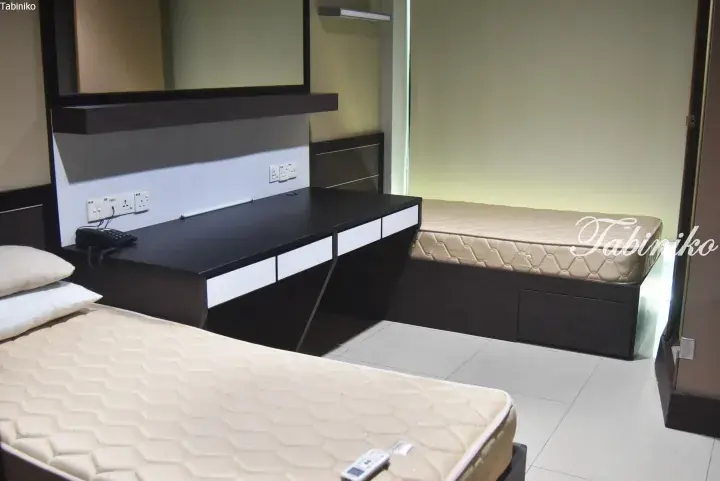 Modern hotel room with twin beds, a black desk with white drawers, and wall-mounted power outlets.