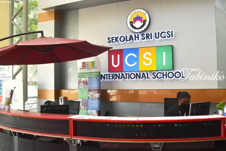Reception area of Sekolah Sri UCSI International School in Kuala Lumpur with a red counter and colorful signage.