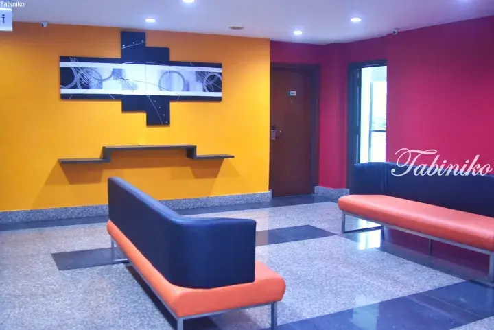Modern hotel lobby with orange and blue seating against vibrant yellow and red walls.