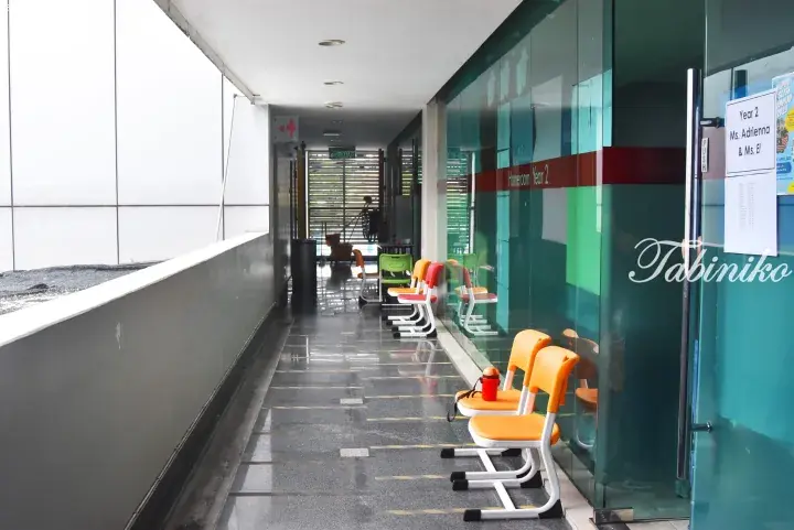 Colorful chairs lined up outside a Year 2 homeroom with glass walls in a modern Malaysian school corridor.