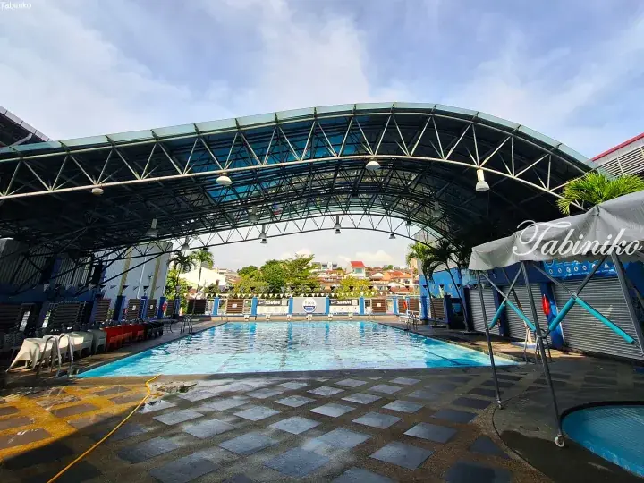 Covered swimming pool with a blue arched roof, lane markers, and lounge chairs at a property.